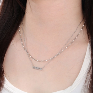 Close-up of double-layer silver MAMA letter pendant necklace on a woman's neckline