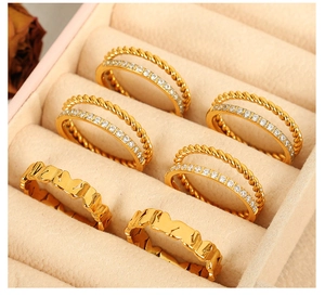 Detail view of gold-plated titanium steel rings with rhinestones in a beige jewelry box