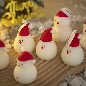 Cute snowman scented candles with red Christmas hats on wooden tray for holiday decor