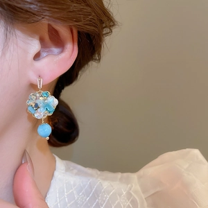 Detailed close-up of light blue floral crystal cluster earrings with round pearl pendant