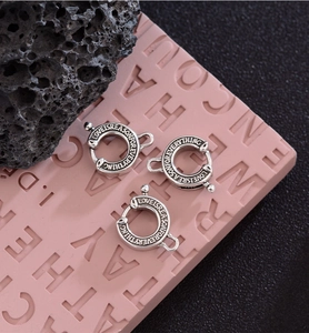 Macro shot of silver horseshoe lobster clasps with engraved love quotes on a pink textured mat