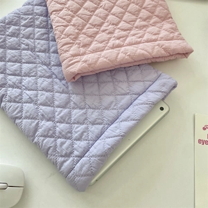 Detailed view of quilted laptop sleeve featuring diamond stitching in purple and pink colors