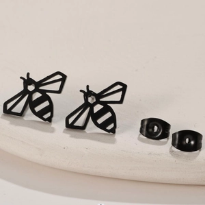 Minimalist black bee stud earrings with matte finish on a stone display plate