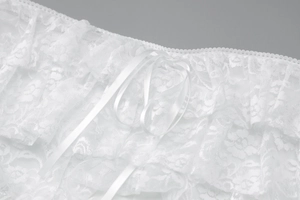 Detailed view of white lace fabric featuring a silky satin ribbon bow tie-up closure