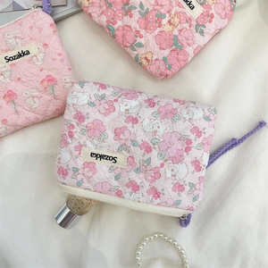 Detail of floral quilted cotton pouch featuring cute rabbit prints and zipper closure