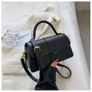 Detail shot of a black PU leather crossbody bag with elegant gold hardware accents