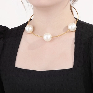 Detailed view of an elegant gold metal choker featuring three large white pearls on a model