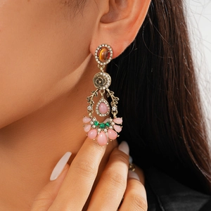 Detail of vintage palace style drop earrings with pink resin stones and bronze metalwork