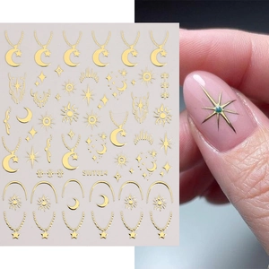 Autocollants d'ongles dorés avec motifs lune, étoile et soleil sur manucure rose