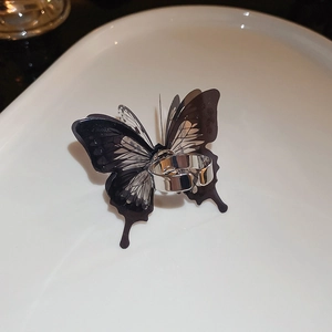 Macro detail of silver-tone butterfly open ring with translucent black wings on white