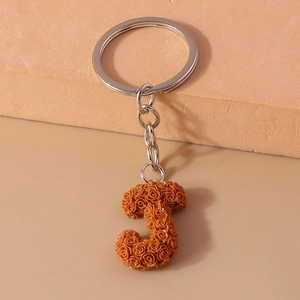 Close-up of letter J keychain with orange resin roses and silver metal ring