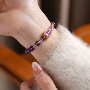Close-up of purple citrine beaded bracelet with a gold gourd pendant on a wrist