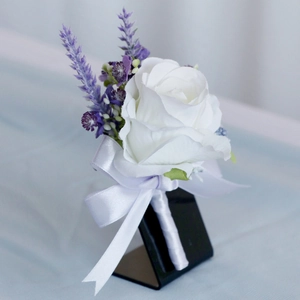 Wedding boutonniere with white rose, purple lavender and white silk ribbon bow on a stand