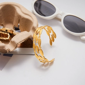 Macro shot of gold-plated fish-shaped layered cuff bracelet with nautical elements