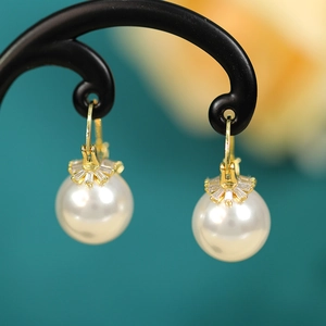 Detailed close-up of elegant pearl drop earrings with sparkling zircon crystals on gold hooks