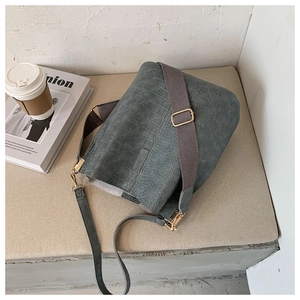 Detail of crocodile embossed bucket bag with wide shoulder strap and gold hardware