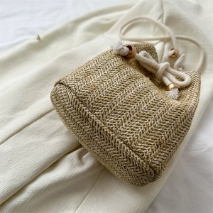 Handwoven straw bucket bag with wooden beads and drawstring closure in natural tones