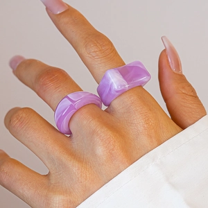 Macro detail of two purple marble resin rings with acrylic texture on a hand