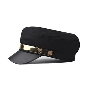Detail of black military cap with faux leather visor and gold M metal buckle decoration