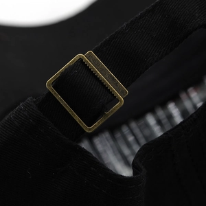 Macro view of adjustable bronze metal buckle and black cotton strap on baseball cap