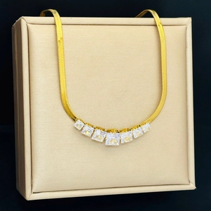 Detail of gold snake chain necklace featuring seven square white zircons on display stand