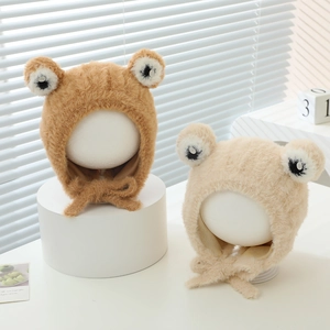 Close-up of brown and beige plush frog earflap hats with soft texture and ties