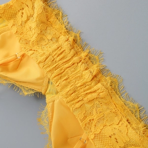 Dettaglio ravvicinato del pizzo floreale giallo e della trama satinata del completo