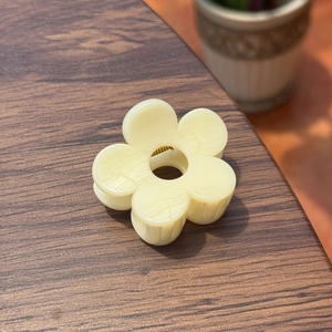 Détail d'une pince à cheveux fleur crème de 5cm avec texture marbrée sur bois