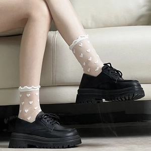 Détail de chaussettes blanches à cœurs avec chaussures noires à semelles compensées