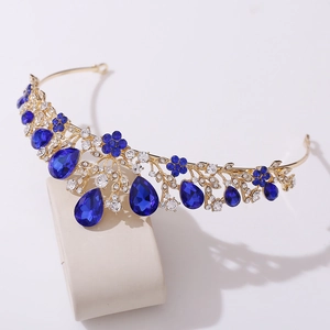Detail of golden crown featuring blue pear-shaped crystals and sparkling floral leaf motifs