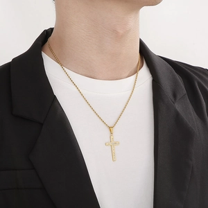 Close-up of gold stainless steel cross necklace with diamonds worn by a male model