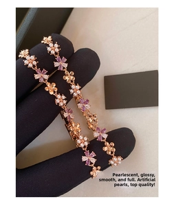 Detail of rose gold flower bracelet with purple crystals and pearls on black velvet glove