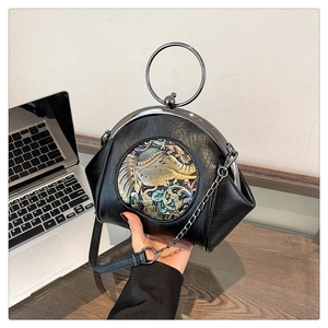Detail of black shell bag featuring a metal round handle and colorful elephant relief