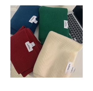 Detail of thick ribbed knit scarves with branded woven labels in various winter colors