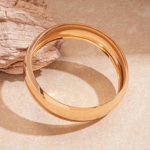 Close-up of three-piece set gold metallic geometric circle bangles on marble surface