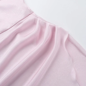 Detailed macro view of pink satin dress fabric with elegant ruffles and jacquard texture