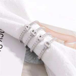 Elegant S925 sterling silver alphabet rings with zircon stones on white fabric