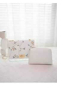Detailed view of white embroidered floral crossbody bag with gold chain and inner pouch