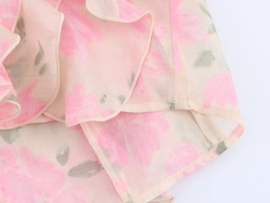 Détail d'un chemisier rose à fleurs avec bords à volants et finitions de couture fines