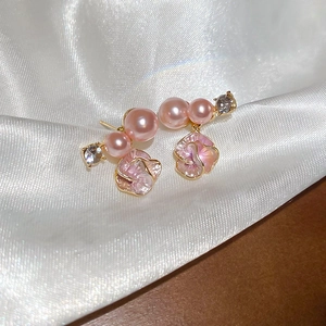 Dettaglio di orecchini a fiore con perle rosa e cristallo su tessuto di raso bianco