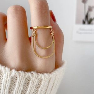 Detail of gold double snake chain tassel ring on hand with elegant knit sweater background