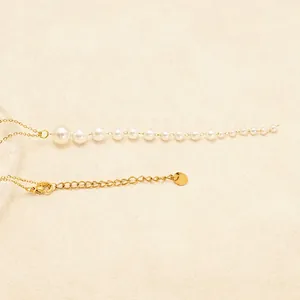 Minimalist 18K gold plated pearl necklace with gradient pearls on a textured background