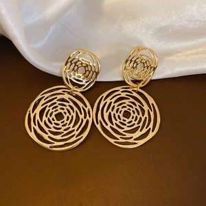 Detail shot of golden geometric hollow rose earrings on elegant silk background