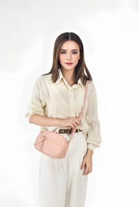 Detailed shot of pink quilted PU leather crossbody bag with adjustable strap on model