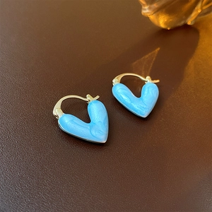 Détail macro de boucles d'oreilles cœur dorées avec émail marbré bleu clair