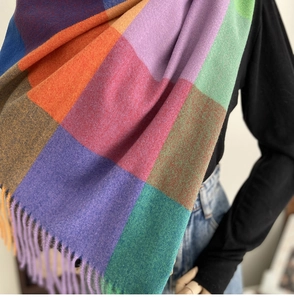 Detail of colorful plaid scarf with long tassels showing rich fiber texture and drape