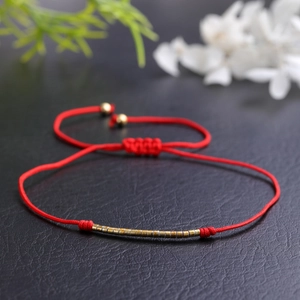 Handmade minimalist red braided string bracelet with gold metallic tubes on black leather