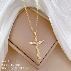 Detail of cross pendant with wings, pink heart stone, and crystal inlay on gold chain