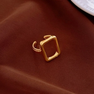 Macro shot of gold plated open ring featuring a hollow rectangle and twisted rope texture