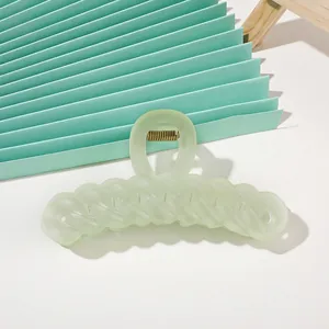Macro detail of a large mint green matte finish chain link hair claw clip on paper fan